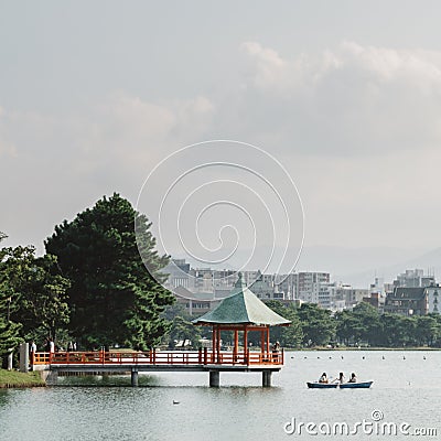 Fukuoka, Japan - A boat and a hexagonal, vermilion pavilion on a large pond at Ohori Park. Stock Photo